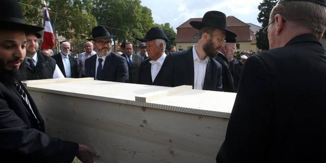 Members of the Jewish community of Strasbourg carry a coffin bearing the remains of a Jewish victim of Nazi anatomist August Hirt, during a ceremony at the Jewish cemetery of Cronenbourg, eastern France, Sunday, Sept. 6, 2015. The remains of Holocaust victims kept for decades in a French medical school were laid to rest on Sunday. (AP Photo/Christian Lutz)