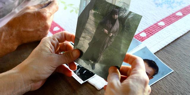 FILE - In this Thursday, Oct. 2, 2014 photo, Severine Ali Mehenni holds pictures of her daughter Sahra, who left to join jihad in Syria, at her home in Lezignan Corbieres, France. France's government is hoping an ad campaign featuring mourning families will make young people think twice about leaving to join extremists in Syria. More than 500 people have left France to join Islamic State and other jihadi groups in the war zones of Syria and Iraq. (AP Photo/ Fred Scheiber, File)