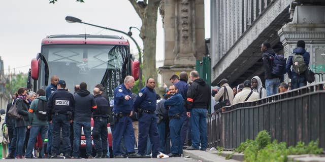 June 2, 2015: Police officers, left, stand near migrants being removed from a tent camp in Paris, France.