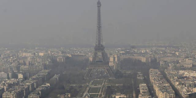 FILE - In this March 14, 2014 file photo, the Eiffel Tower, is photographed through the smog in Paris. Paris police have lowered speed limits and ordered a halt to trash burning Wednesday, March 18, 2015 as part of emergency measures triggered by a spike in air pollution — months before the city hosts a major international climate conference. (AP Photo/Jacques Brinon, File)
