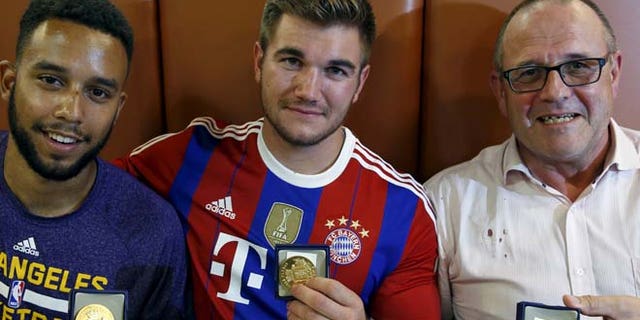 Three men who helped to disarm an attacker on a train from Amsterdam to France, Anthony Sadler, from Pittsburg, California, Aleck Sharlatos from Roseburg, Oregon, and Chris Norman, a British man living in France, pose with medals they received for their bravery at a restaurant in Arras.