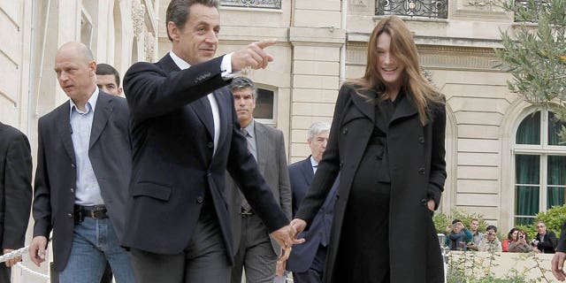 French President Nicolas Sarkozy, center, and his wife Carla Bruni-Sarkozy, left, walk in the gardens of the Elysee Palace in Paris during 28th edition of France's Day of Patrimony, Saturday, Sept. 17, 2011. France opens the doors of its state buildings as part of its Day of Patrimony when usually these buildings would be forbidden to the public.