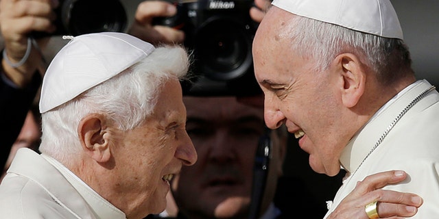An ISIS propaganda video shows photos of Pope Benedict XVI, left, and Pope Francis being torn in half.