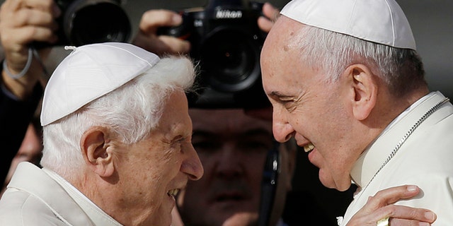 An ISIS propaganda video shows photos of Pope Benedict XVI, left, and Pope Francis being torn in half.