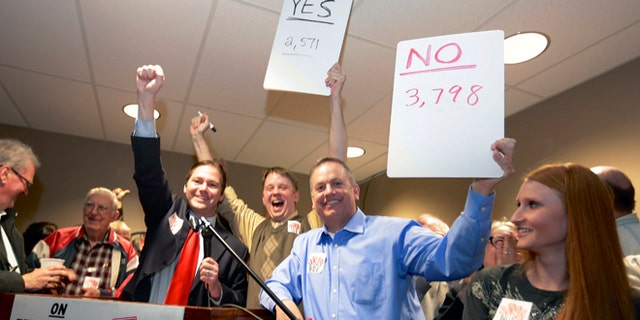 FILE - In this file photo from Feb. 11, 2014, State Sen. Charlie Jansssen of Fremont, third left, Jeremy Jensen, center, and John Wiegert, second right, celebrate in Fremont, Neb., after city voters have decided by voting no, to uphold the law designed to bar immigrants from renting homes if they dont have legal permission to be in the U.S.  On Monday, May 5, 2014, the U.S. Supreme Court decided not to review Fremont's ordinance that bans renting homes to immigrants living in the country illegally. Supporters of the ordinance said it could open the door to similar laws elsewhere. (AP Photo/Nati Harnik, File)