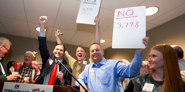 FILE - In this file photo from Feb. 11, 2014, State Sen. Charlie Jansssen of Fremont, third left, Jeremy Jensen, center, and John Wiegert, second right, celebrate in Fremont, Neb., after city voters have decided by voting no, to uphold the law designed to bar immigrants from renting homes if they dont have legal permission to be in the U.S. On Monday, May 5, 2014, the U.S. Supreme Court decided not to review Fremont's ordinance that bans renting homes to immigrants living in the country illegally. Supporters of the ordinance said it could open the door to similar laws elsewhere. (AP Photo/Nati Harnik, File)
