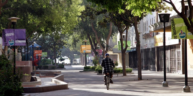 In this photo taken on Friday Sept. 20, 2013 in Fresno, Calif., a man rides his bike on the Fulton Mall, a six-block pedestrian mall once touted as a national model for pedestrian-friendly downtowns. While many U.S. cities are converting urban cores into walkable oases, Fresno leaders want to convert the struggling pedestrian mall back into a street. (AP Photo/Gosia Wozniacka)
