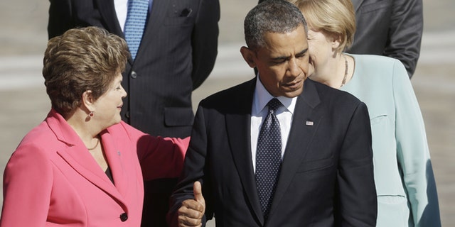 US President Barack Obama, right, gives a 'thumbs-up' sign as he waits with other leaders for Russia's President Vladimir Putin to take the group photo at the G-20 summit at the Konstantin Palace in St. Petersburg, Russia, Friday, Sept. 6, 2013. Greeting each other behind Obama are Brazil's President Dilma Rousseff, left, and Germany's Chancellor Angela Merkel. (AP Photo/Pablo Martinez Monsivais)