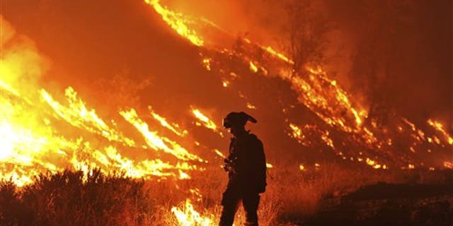 In this Aug. 3, 2015, file photo, CalFire Firefighter Bo Santiago lights a backfire as the Rocky fire burns near Clearlake, Calif. (AP Photo)
