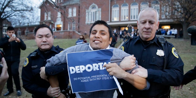 Marco Malagon is removed from the venue by Des Moines police officers after protesting during former Texas Gov. Rick Perry's speech at the Freedom Summit, Saturday, Jan. 24, 2015, in Des Moines, Iowa. (AP Photo/Charlie Neibergall)