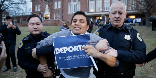 Marco Malagon is removed from the venue by Des Moines police officers after protesting during former Texas Gov. Rick Perry's speech at the Freedom Summit, Saturday, Jan. 24, 2015, in Des Moines, Iowa. (AP Photo/Charlie Neibergall)