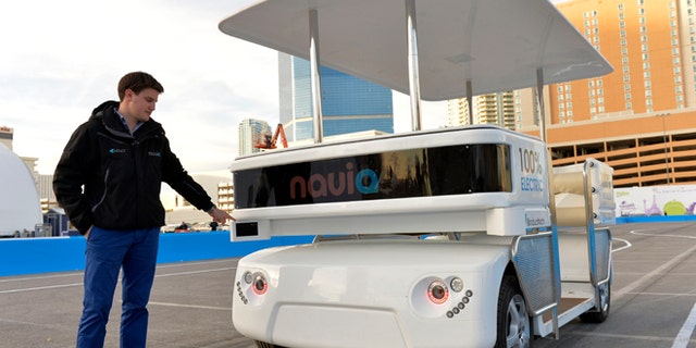 Raphael Gindrat, from Induct, points to a guidance laser while demonstrating their new Navia driverless shuttle at the International Consumer Electronics Show, Monday, Jan. 6, 2014, in Las Vegas. (AP Photo/Jack Dempsey)