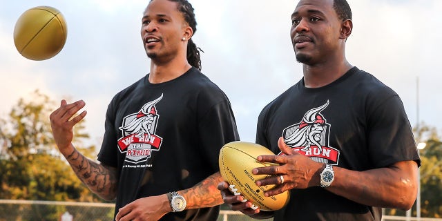 Former NFL players Jabar Gaffney, left, and Lito Sheppard present golden footballs during a Super Bowl High School Honor Roll ceremony at their alma mater William M. Raines High School in 2015