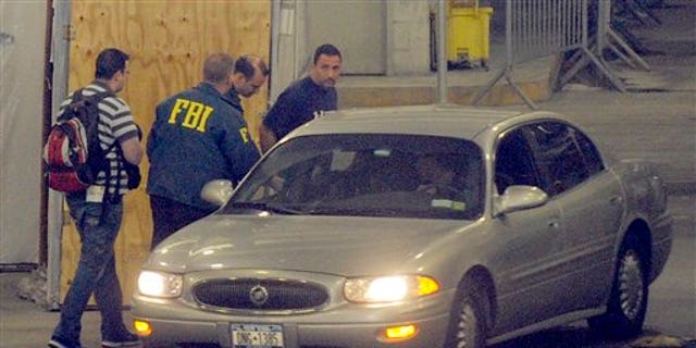 June 2: Richard Palase, standing right, a New York City Police Department detective, was one of 15 people, including two firefighters, who were arrested in connection with a New York City gambling ring, according to federal authorities, in New York. Palase is seen being transferred by FBI agents in the garage of the Jacob K. Javits Federal Building. (AP)