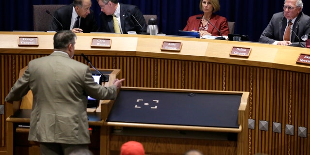 July 15, 2014: Denton, Texas Council member George Campbell, left rear, talks with Mayor Chris Watts as council members Anita Burgess and Dalton Gregory right, listen to former Texas Railroad Commission executive director John Tintara, at lectern, speak at a public hearing at City Hall. (AP Photo/Tony Gutierrez)