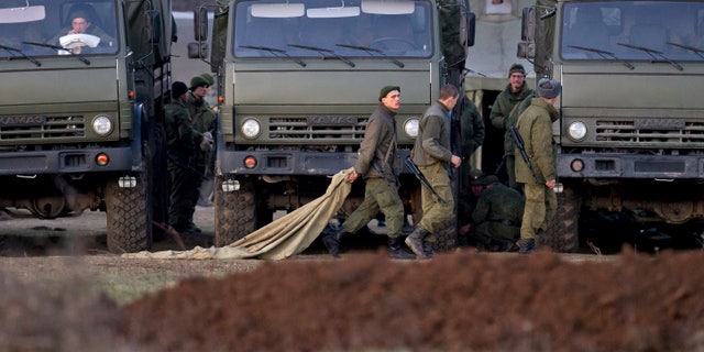 March 15, 2014: Pro-Russian soldiers walk past trucks that define the limits of their staging area in the vicinity of a Ukrainian military base in Perevalne, Ukraine.