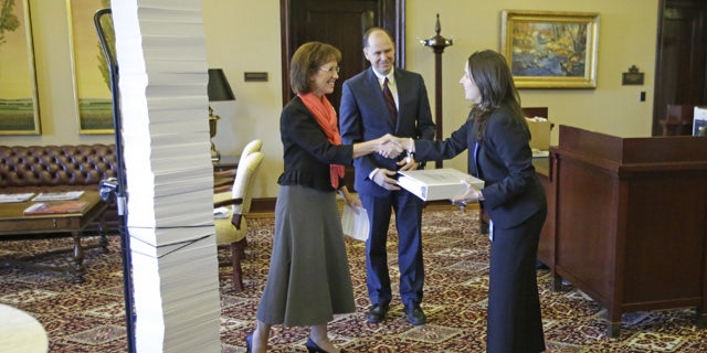 September 5, 2014: Opponents of same-sex marriage Laura Bunker, left, with the United Families International and Bill Duncan, of the Sutherland Institute, give Tiffany Clason, right, an employee of Gov. Gary Herbert's office, a list of 18,600 names of people who signed online petitions supporting traditional marriage and Utah's defense of its gay marriage ban during a meeting at the Utah State Capitol in Salt Lake City. (AP Photo/Rick Bowmer)
