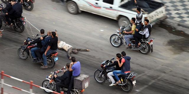 Nov. 20, 2012: Palestinian gunmen ride motorcycles in Gaza City as they drag the body of a man who was suspected of working for Israel.