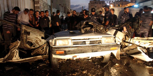 Nov. 17: Palestinians gather around a destroyed car after an explosion in Gaza City.