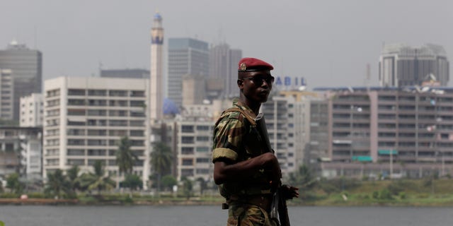 Jan. 9, 2011: Against a backdrop of Abidjan's central Plateau district, a soldier provides security at a rally in support of incumbent president Laurent Gbagbo, at the Palace of Culture in Abidjan, Ivory Coast. Former Nigerian President Olusegun Obasanjo was shuttling between meetings Sunday with the country's defiant president who refuses to cede power and the internationally recognized winner in the latest effort to resolve the post-election crisis. (AP)