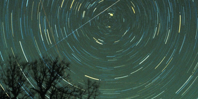 A Geminid meteor streaks across the sky.