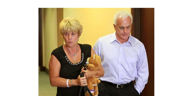 Cindy Anthony, sosteniendo un oso de peluche, y su esposo, George Anthony, abandonan la sala del tribunal después de escuchar la primera parte de los argumentos iniciales del estado en el juicio por asesinato en primer grado de su hija en el Tribunal del Condado de Orange el 24 de mayo en Orlando, Florida.