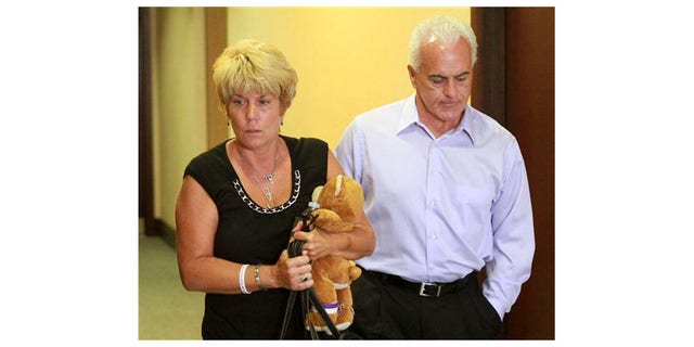 Cindy Anthony, sosteniendo un oso de peluche, y su esposo, George Anthony, abandonan la sala del tribunal después de escuchar la primera parte de los argumentos iniciales del estado en el juicio por asesinato en primer grado de su hija en el Tribunal del Condado de Orange el 24 de mayo en Orlando, Florida.