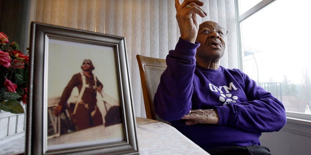FILE 2009: George Hickman, in Seattle, sits near a photo of himself in the cockpit of an AT6 trainer airplane.