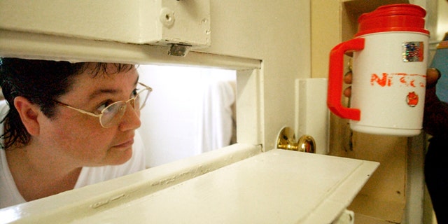 July 6, 2004: In this file photo, Kelly Gissendaner, the only woman on Georgia's death row, peers through the slot in her cell door as a guard brings her a cup of ice at Metro State Prison in Atlanta. (AP/Atlanta Journal-Constitution, Bita Honarvar, File)