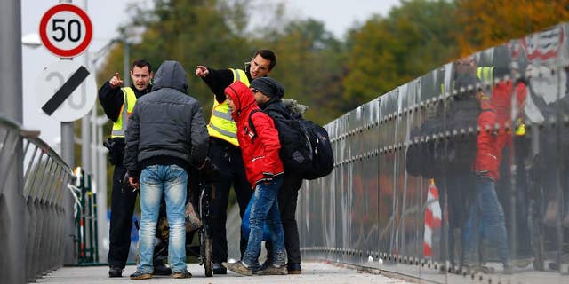 German federal police officers talk to arriving migrants on a bridge at the border between Austria and Germany in Freilassing near Salzburg, Germany, Tuesday, Oct. 13, 2015. (AP Photo/Matthias Schrader)