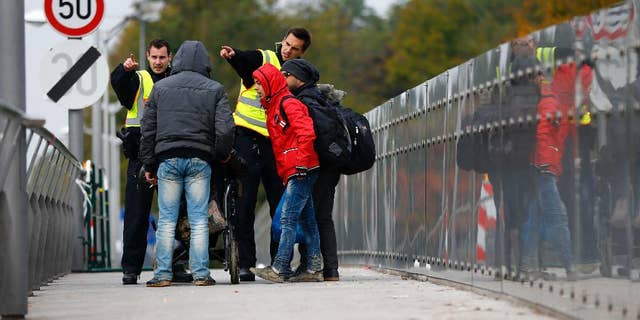 German federal police officers talk to arriving migrants on a bridge at the border between Austria and Germany in Freilassing near Salzburg, Germany, Tuesday, Oct. 13, 2015. (AP Photo/Matthias Schrader)