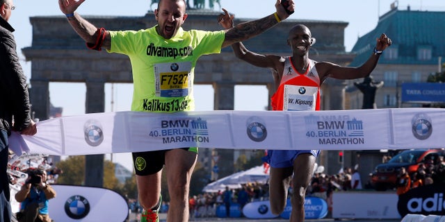 Sept. 29, 2013 - Winner Wilson Kipsang, right, from Kenya smiles as an unidentified man crosses the finish line during the 40th Berlin Marathon in Berlin, Germany. Kipsang set a new world record of 2h 3min 23sec.