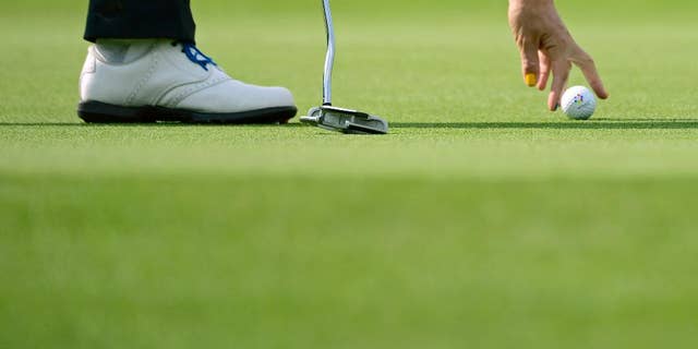 A European player places a ball in the foursomes on Day1 at the Solheim Cup golf tournament in St. Leon-Rot, southern Germany, Friday, Sept. 18, 2015. (AP Photo/Jens Meyer)