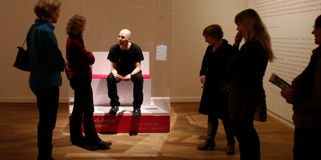 March 22, 2013 FILE photo: Visitors surround Ido Porat, the 1st person acting as the "Jew in a glass box," at the exhibition "The Whole Truth- everything you always wanted to know about Jews" at the Jewish Museum in Berlin.