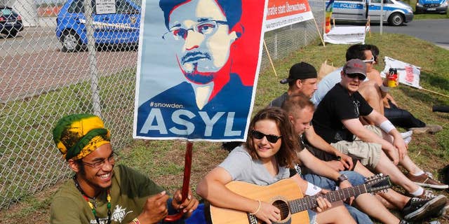 A demonstrator against spying holds a sign asking for asylum for former NSA contractor Edward Snowden outside US Army's 'Dagger Complex' near Griesheim, Germany, Saturday, July 26, 2014. The massively secured property is run by the US Military and supposed to be used by the US intelligence agency NSA (National Security Agency). (AP Photo/Michael Probst)(AP Photo/Michael Probst)