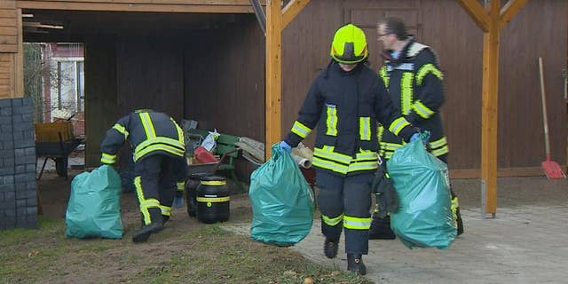 Firefighters carry plastic bags in a garden in Preetz near Kiel, northern Germany, Tuesday afternoon, Feb. 24, 2015. Workers clearing a small garden property in northern Germany got a shock when they unearthed a rusted can labeled “Zyklon B” _ the deadly poison gas used by the Nazis in the death chambers of Auschwitz and other camps. Emergency crews were able to determine the can was empty, but still sealed it and removed it as a precaution. (AP Photo/dpa, Daniel Friederichs)