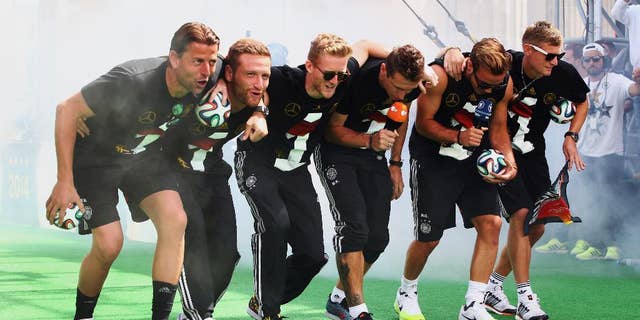 German soccer players from left: Roman Weidenfeller, Shkodran Mustafi, Andre Schuerrle, Miroslav Klose, Mario Goetze and Toni Kroos celebrate on stage at the German team victory ceremony , near the Brandenburg Gate in Berlin, Tuesday July 15, 2014. Germany's World Cup winners shared their fourth title with hundreds of thousands of fans by parading the trophy through cheering throngs to celebrate at the Brandenburg Gate on Tuesday. An estimated 400,000 people packed the "fan mile" in front of the Berlin landmark to welcome home coach Joachim Loew's team and the trophy — which returned to Germany for the first time in 24 years. (AP Photo/ Alex Grimm,Pool)