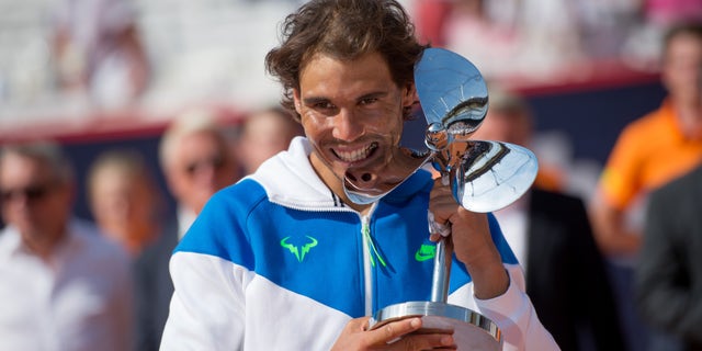 Spain's Rafael Nadal celebrates with the trophy after he won the final match of the Hamburg Open ATP tennis tournament against Fabio Fognini of Italy, in Hamburg, Germany, Sunday Aug. 2, 2015. (Daniel Reinhardt/dpa via AP)
