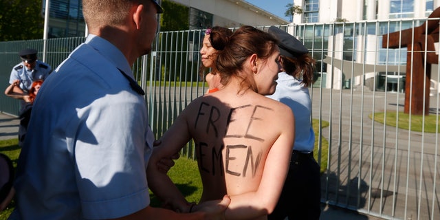 June 7, 2013: Activists from the women's movement Femen are being stopped by police officers during a protest in front of the German chancellery ahead of the visit of Tunisian Prime Minister Ali Laarayedh in Berlin. Three topless Femen protesters pleading for Angela Merkel to push for the release of four fellow activists jailed in Tunisia.