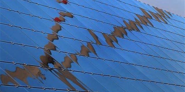 A wind turbine is reflected in the panels of a solar field in Biebelried, Germany, in 2013.