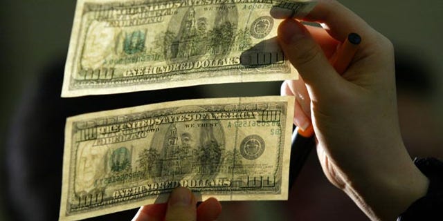 SEOUL, SOUTH KOREA - FEBRUARY 23: South Korean lawmaker Kim Moon-Soo shows a genuine U.S. $100 note above a counterfeit one during a news conference at the National Assembly February 23, 2006 in Seoul, South Korea. Kim, who obtained the counterfeit through human rights activists in the Chinese city of Dandong bordering North Korea, is urging the South Korean government to deal with North Korea's alleged counterfeiting more sternly. (Photo by Chung Sung-Jun/Getty Images)