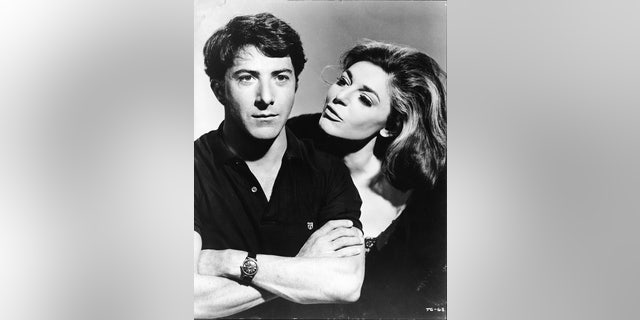American actress Anne Bancroft (1931 - 2005), in character as the seductive older woman Mrs. Robinson, looks at American actor Dustin Hoffman, as Benjamin Braddock, in a publicity still from the film 'The Graduate' directed by Mike Nichols, California, 1967.