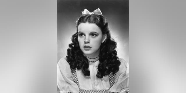 1939:  Promotional studio portrait of American actor and singer Judy Garland (1922 - 1969) wearing her costume as Dorothy from director Victor Fleming's film, 'The Wizard of Oz'.  She wears a gingham bodice and a white puff-sleeved blouse, with a satin ribbon in her hair.  (Photo by MGM Studios/MGM Studios/Getty Images)
