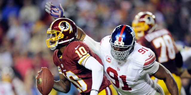 Washington Redskins quarterback Robert Griffin III (10) is pressured by New York Giants defensive end Justin Tuck (91) during the second half of an NFL football game Sunday, Dec. 1, 2013, in Landover, Md. The Giants won 24-17. (AP Photo/Nick Wass)