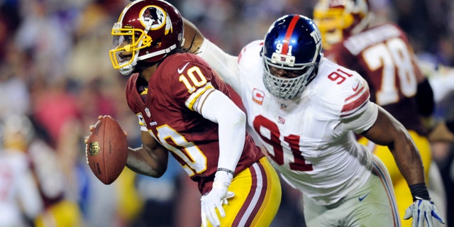 Washington Redskins quarterback Robert Griffin III (10) is pressured by New York Giants defensive end Justin Tuck (91) during the second half of an NFL football game Sunday, Dec. 1, 2013, in Landover, Md. The Giants won 24-17. (AP Photo/Nick Wass)