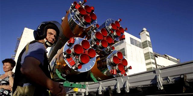 A Russian police officer stands guard as the Russian Soyuz TMA-19 space ship that will carry new crew to the international space station is transported from a hangar to the launch pad at the Russian-leased Baikonur Cosmodrome in Baikonur, Kazakhstan, Sunday, June 13, 2010.