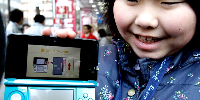 Feb. 26, 2011: Natsumi Miyasaka, 9, shows off Nintendo's newest computer game console, the Nintendo 3DS, at retail store Bic Camera in central Tokyo.