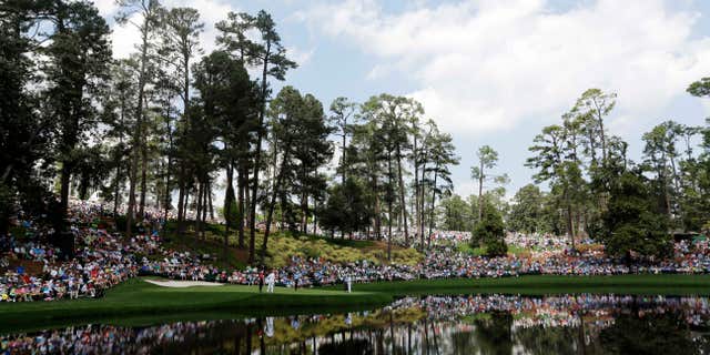 April 8, 2015: Spectators sit around the ninth hole during the Par 3 contest at the Masters golf tournament.