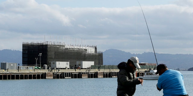 Oct. 29, 2013: Two men fish in the water in front of a Google barge on Treasure Island in San Francisco.