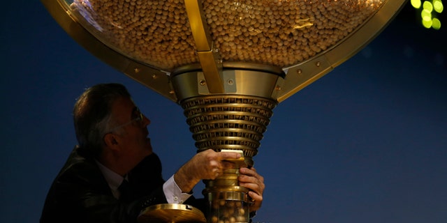 A worker opens a trap-door in a giant drum to let the balls bearing ticket numbers fall into a lower compartment before the start of Spain's Christmas lottery, in Madrid, Tuesday, Dec. 22, 2015. Celebrations were guaranteed Tuesday in the southern beach town of Roquetas de Mar, southern east Spain, where tickets bearing the top prize number of 79140 in Spain's Christmas lottery, known as "El Gordo" (The Fat One) were sold. The number appeared on 1,600 tickets, known as decimos (tenths) with each holder winning 400,000 euros ($434,800). The tickets are usually sold in many different lottery sales points making it virtually impossible to win the entire 640 million euros assigned to the top prize number. (AP Photo/Francisco Seco)